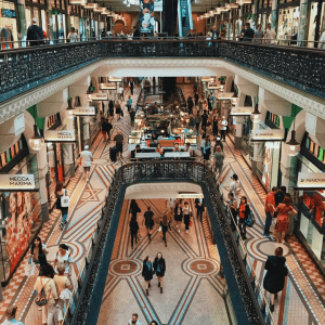 Auf diesem Bild ist ein Einkaufszentrum von innen zu sehen, mit vielen Menschen und Geschäften.